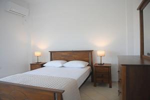 a bedroom with a bed with two night stands and two lamps at Icaria Great Filling House in Evdilos
