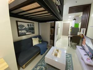uma sala de estar com um sofá azul e uma mesa em Staycation w/ Free Pool at Victoria Sports em Manila