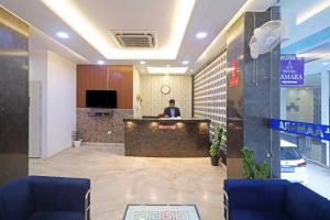 a man sitting at a counter in a lobby at Hotel Mayda Prime Near Delhi Airport in New Delhi