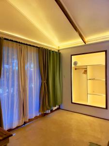 a room with a window with green curtains and a mirror at Kawai Duli Bungalows 1 in Duli