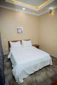 sypialnia z dużym łóżkiem z białą pościelą i poduszkami w obiekcie Ridge Estates w mieście Dar es Salaam