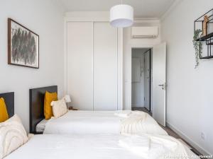 two beds in a bedroom with white walls and yellow pillows at Akicity Campolide Sun in Lisbon