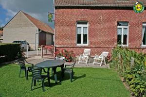 Henneveux的住宿－Le Gîte du Bois Groult，砖砌建筑前带桌椅的庭院