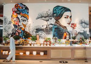a man walks past a store with a mural of two women at PANORAMA OCEANFRONT SUITE in Nha Trang