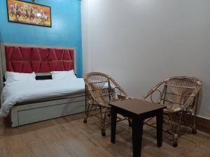 1 dormitorio con 1 cama, 2 sillas y mesa en Paradise Home stay, en Rāni Pokhri