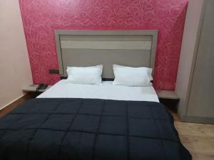 1 cama con 2 almohadas y pared rosa en Paradise Home stay, en Rāni Pokhri