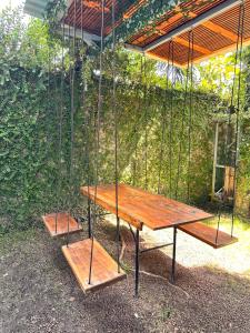 a picnic table with a swing and two benches at Hotel Bamboo in Jacó
