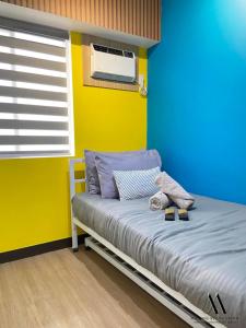 1 dormitorio con 1 cama con pared azul y amarilla en Maxine Staycation, en Manila
