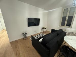 sala de estar con sofá negro y TV de pantalla plana en Appartement VIII - Haut Standing proche Luxembourg et Cattenom, en Nilvange