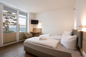 sypialnia z łóżkiem i dużym oknem w obiekcie Hotel Seebrücke w mieście Lubmin
