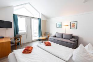 Habitación de hotel con 2 camas y sofá en Hotel Seebrücke, en Lubmin