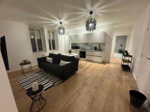 sala de estar con sofá negro y cocina en Appartement VIII - Haut Standing proche Luxembourg et Cattenom, en Nilvange