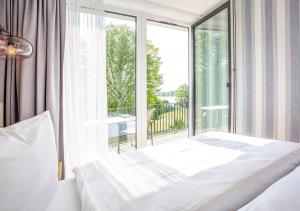 a bedroom with a bed and a large window at Maremüritz Yachthafen Resort in Waren