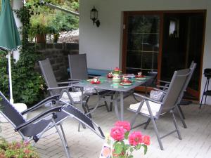 a table and chairs on a patio with roses at Ferienwohnung im Harz-Haus-Bruns in Clausthal-Zellerfeld