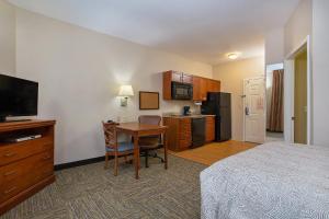 a hotel room with a bed and a desk with a table at Candlewood Suites Tuscaloosa, an IHG Hotel in Tuscaloosa