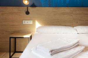 a bedroom with a white bed with a wooden headboard at Font Andorra Hostel in La Massana