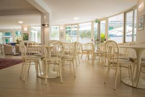 ein Esszimmer mit weißen Stühlen und Tischen und Fenstern in der Unterkunft Hotel Lady G in Tortoreto Lido