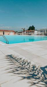 a blue swimming pool with a shadow on the ground at Camping Europcamping in Fréjus