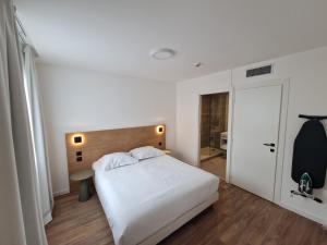 sypialnia z białym łóżkiem z drewnianym zagłówkiem w obiekcie Appart'hôtel Marianne w Montpellier