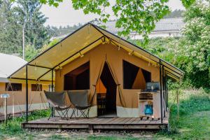 a yellow tent with chairs on a wooden deck at Onlycamp L'Orée des Vosges in Le Val-dʼAjol