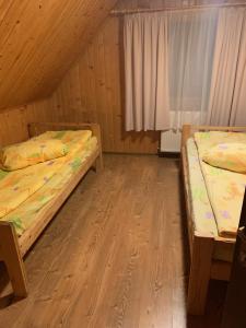 two beds in a room with wooden floors at Hargitafürdői Vendégház in Harghita-Băi