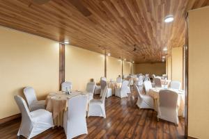 Habitación con mesas y sillas blancas y techos de madera. en Tehri Club Resort By DLS Hotels, en Chamba