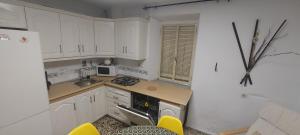 una pequeña cocina con armarios blancos y sillas amarillas en Casa Rural Lunares y Salinera en Albanchez de Úbeda