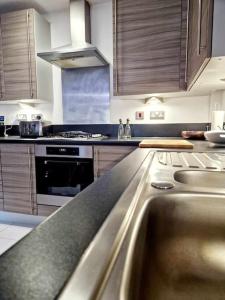a kitchen with wooden cabinets and a stainless steel counter top at Explore London: 2 Bedroom House in Wood Green in London