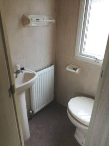 a bathroom with a toilet and a sink and a window at Midden Manor: Farm stay in rural County Antrim. in Cullybackey