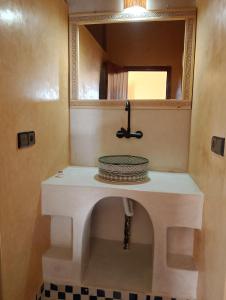 ein Bad mit einem Waschbecken und einem Spiegel in der Unterkunft Auberge L'oasis in Merzouga