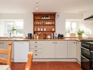 uma cozinha com armários brancos e um fogão em Cliff Cottage em Thirsk