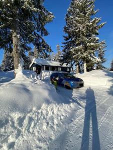 un coche aparcado en la nieve frente a una casa en Hytte til leie på Budor, en Nordset