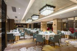 a dining room with white tables and chairs at Ramada Plaza Liuzhou Liudong in Liuzhou