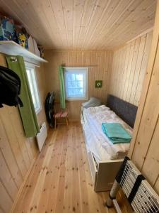 una piccola camera da letto con un letto in una camera in legno di Høstkos og ro på Budor, 4 roms hytte med peis og wifi a Nordset