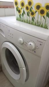een witte wasmachine met een schilderij van zonnebloemen erop bij Acogedor apartamento JV36 in Córdoba