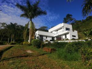 a white house with a palm tree in front of it at Habitación en casa Rural Campestre in La Vega