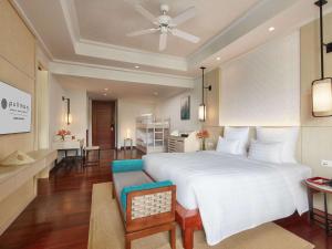 a bedroom with a large white bed and a living room at Pullman Danang Beach Resort in Da Nang