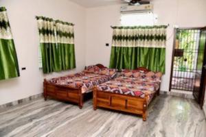 two beds in a room with green curtains at Spacious Guesthouse in Nagercoil in Nāgercoil