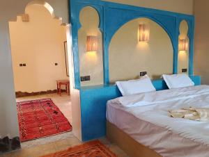 Bett mit blauem Kopfteil in einem Zimmer in der Unterkunft Auberge L'oasis in Merzouga