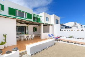 een villa met witte muren en een patio met stoelen bij Famara Caracolillos, La Casa in Famara