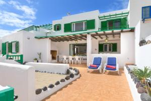 une villa avec une terrasse et des chaises bleues dans l'établissement Famara Caracolillos, La Casa, à Famara