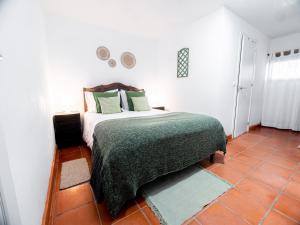 a bedroom with a bed with a green blanket at VILA NATURA in Barreiro