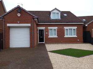 a brick house with a garage and a grass at No. 5 in Hartlepool