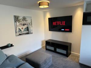 a living room with a couch and a tv on the wall at modern 1 bed apartment with car parking in Bitton