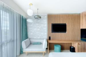 a living room with a couch and a tv at GOLDEN TULIP LYON OUEST TECHLID Hotel & Spa in Limonest