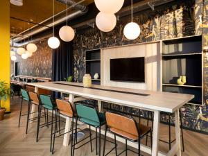 a bar with chairs and a large table in a room at ibis Styles Copenhagen Orestad in Copenhagen