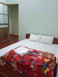 a bed with a red blanket on top of it at Hải Phận Homestay in Ha Giang