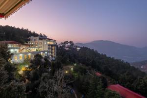 un edificio en una colina con montañas en el fondo en Tehri Club Resort By DLS Hotels, en Chamba