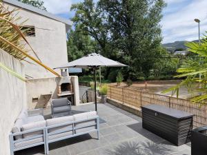 a patio with a table and an umbrella at Gîte Molly in Entraygues-sur-Truyère