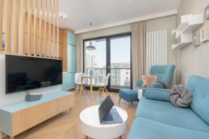 ein Wohnzimmer mit einem blauen Sofa und einem TV in der Unterkunft Bright Blue Apartment with Balcony, Parking and Air Conditioning in Warsaw by Renters in Warschau